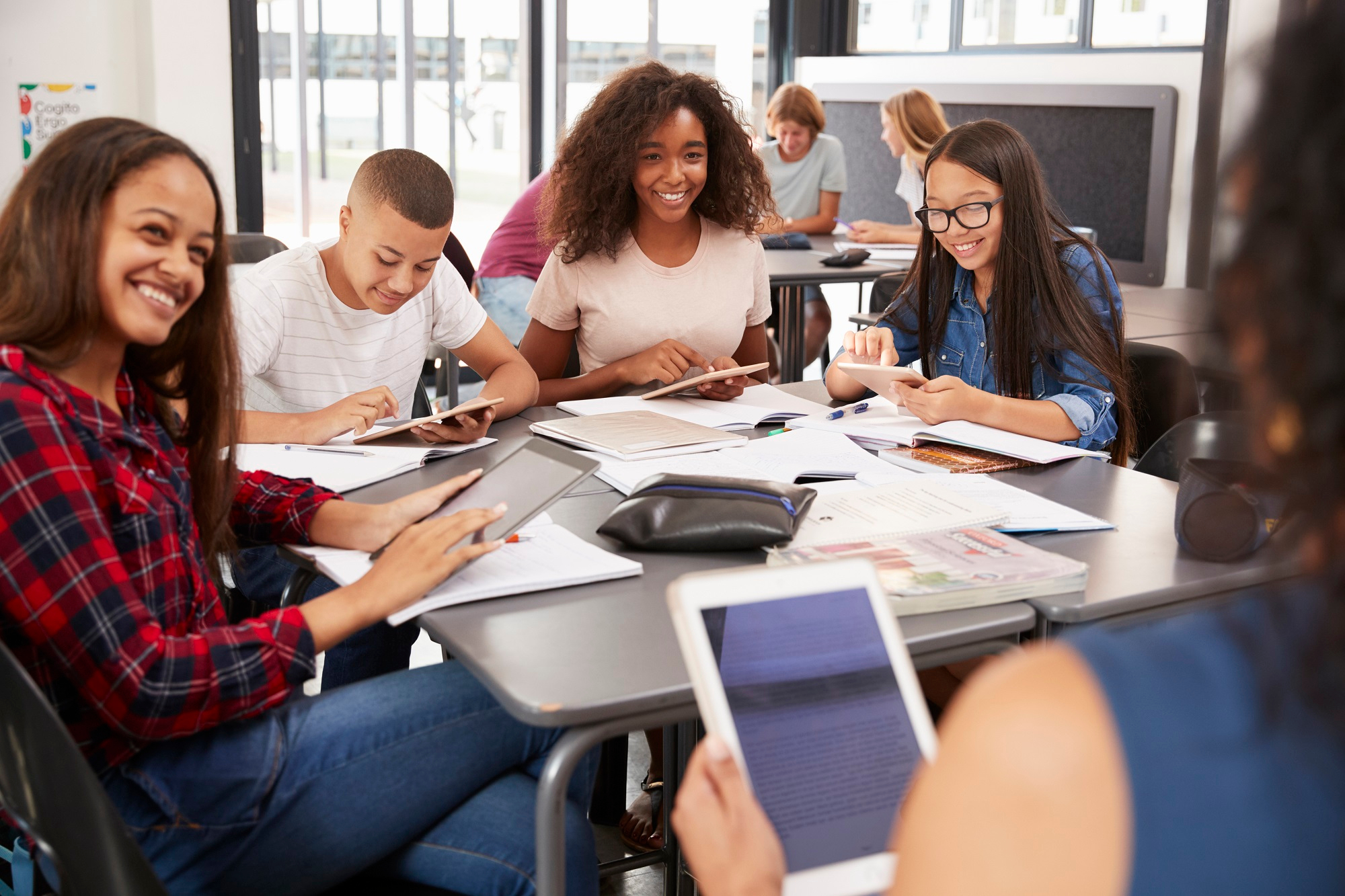 Eine Gruppe Schüler*innen bei der Textarbeit an Tablets.